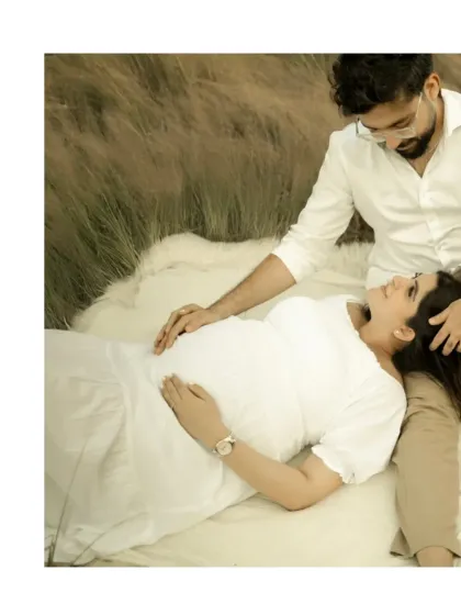 A tender moment of connection. The couple lies on a soft blanket outdoors, sharing a loving gaze, a simple and beautiful portrait of their bond.