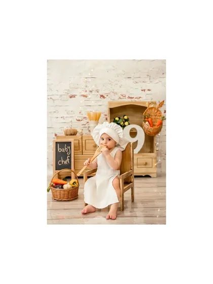 A nine-month milestone for this little chef. He's tasting the wooden spoon, an adorable and authentic moment from our kitchen-themed shoot.