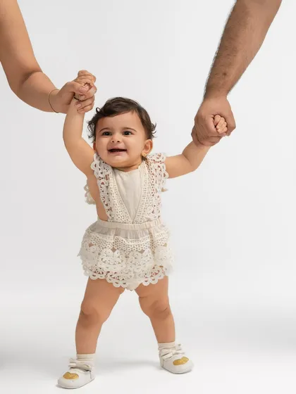 A baby takes her first tentative steps while holding her parents' hands. Capturing these major milestones is a key part of documenting your family's journey.