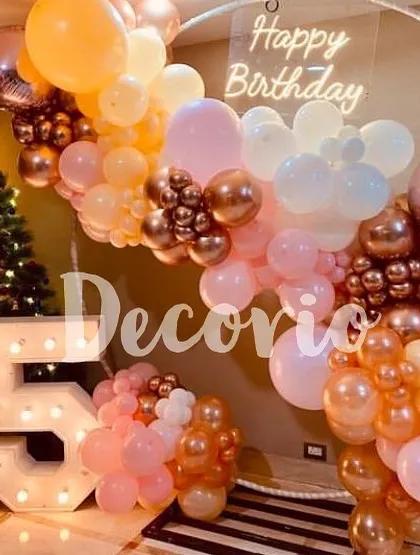 A beautiful 25th birthday party featuring a circular backdrop with a neon sign. The decor is brought to life with large marquee numbers and a pastel and rose gold balloon arrangement.