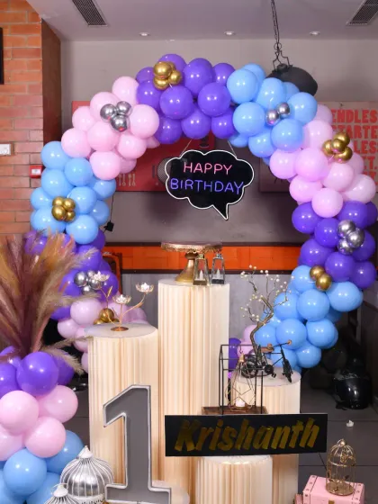 The balloon arch for this first birthday uses a beautiful color palette of purple, light blue, and baby pink with chrome accents.