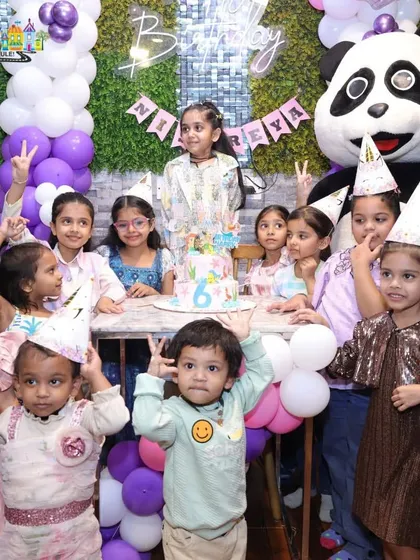 A group of happy kids celebrating at a mermaid-themed party, complete with party hats and a surprise visit from our panda mascot.