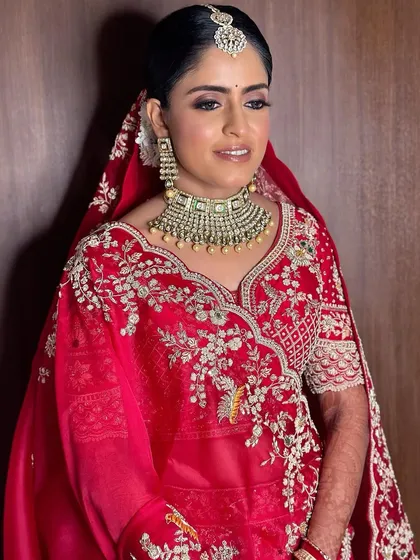 Surabhi's side profile, highlighting the clean lines of her makeup and the intricate details of her bridal jewelry.