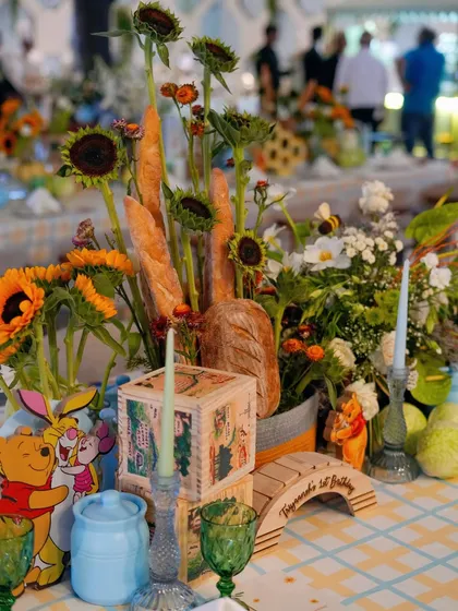 A unique centerpiece combining fresh baguettes, sunflowers, and Winnie the Pooh characters, perfectly capturing the rustic charm of the theme.