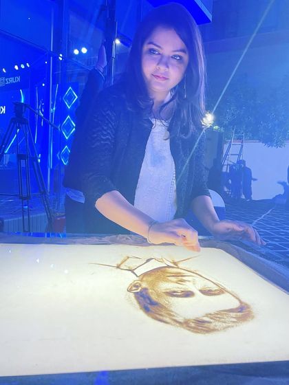 A close-up shot of me working on a portrait during a corporate sand art show. The lighting and atmosphere of each event add a unique feel to the performance.