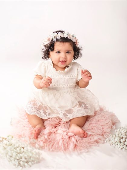 This eleven-month-old looks so sweet and angelic in her white lace dress and floral headband, just one month shy of her first birthday.