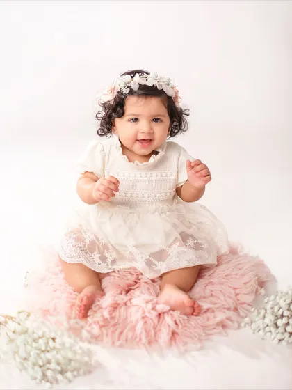 This eleven-month-old looks so sweet and angelic in her white lace dress and floral headband, just one month shy of her first birthday.
