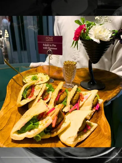 An artfully presented platter of Falafel in Pita with Hummus, complete with a floral garnish. This dish transports your guests to the Middle East with its authentic flavors and textures.