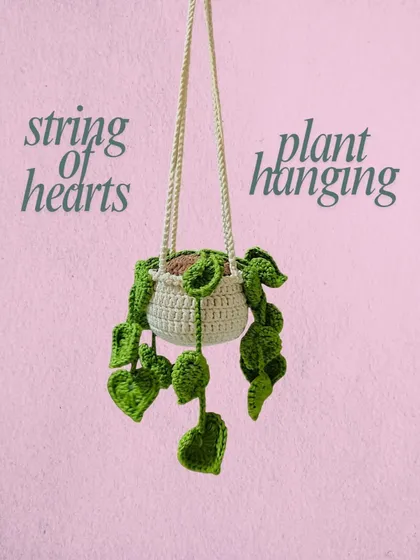 This string of hearts hanging plant is a beautiful piece of room decor that you never have to worry about watering. The heart-shaped leaves are all crocheted by hand and hang from a little pot.