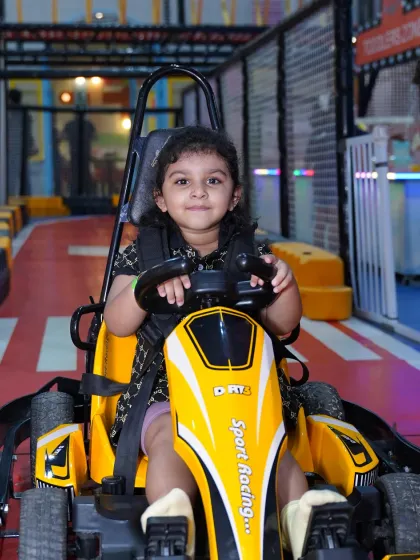 A smile that says it all. This little one is enjoying her first taste of the driver's seat in our yellow sport racing go-kart, perfectly sized and speed-controlled for our youngest guests.