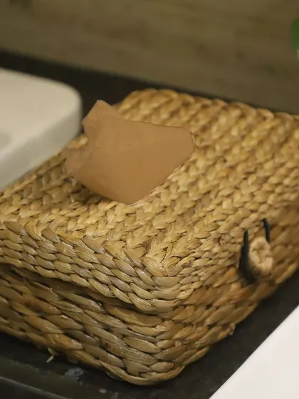 Our woven tissue box cover, made from natural water hyacinth, is shown here on a bathroom counter. It's a simple way to add a touch of organic texture and spa-like calm to your bathroom decor.