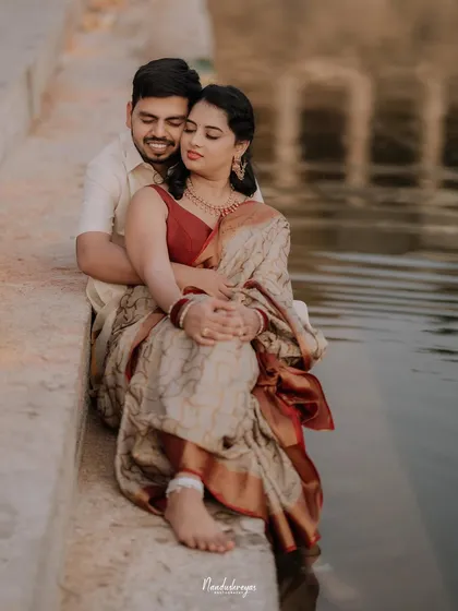 A tender moment by the water's edge, with the couple embracing as the bride dips her feet in the pond.