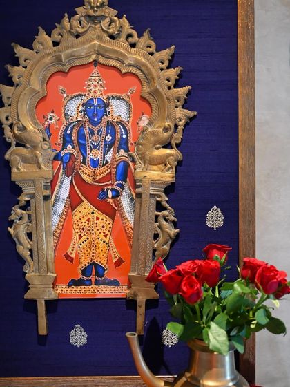 A close-up of the Vishnu artwork within the restored family heirloom Prabhavali. The vibrant orange background and the rich blue of the silk create a stunning contrast, highlighting the divine figure.
