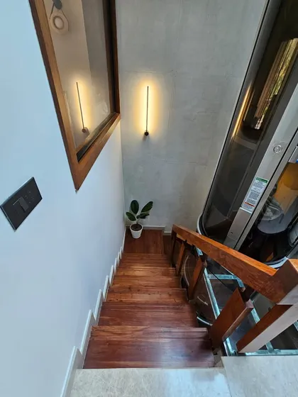 This high-angle view showcases a sleek, all-glass vacuum elevator we integrated alongside a wooden staircase. This feature is a testament to our ability to blend cutting-edge technology with timeless materials, providing elegant and practical solutions for multi-level homes.