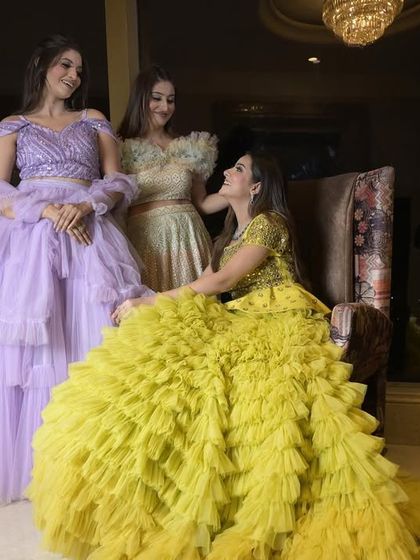 A group of clients showcasing my multi-layered ruffle gowns. This image features a vibrant yellow gown, a pastel lavender dress, and a light green piece, all with voluminous, textured skirts.