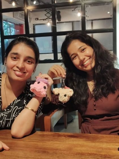 Two friends showing off the cute crochet keychains they made. A handmade memory of a great day spent together.