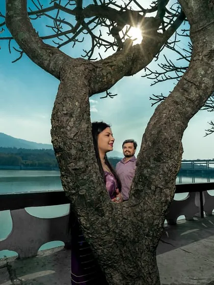 Peeking through the branches of a tree to find the couple sharing a moment. This creative framing adds depth and an element of discovery to the photograph.