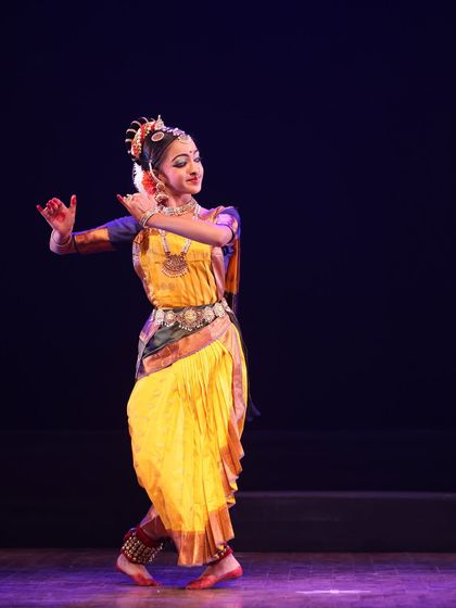 A student captured in a graceful pose that highlights the intricate details of the costume and the elegance of the dance form.