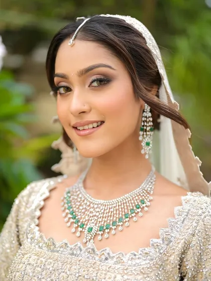 A close-up on the details. The soft brown smokey eye and perfectly groomed brows frame her face, while the glowing skin completes this modern bridal look.