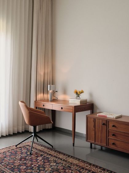 A functional and stylish home office setup with a mid-century modern desk and credenza, complemented by a classic patterned rug.