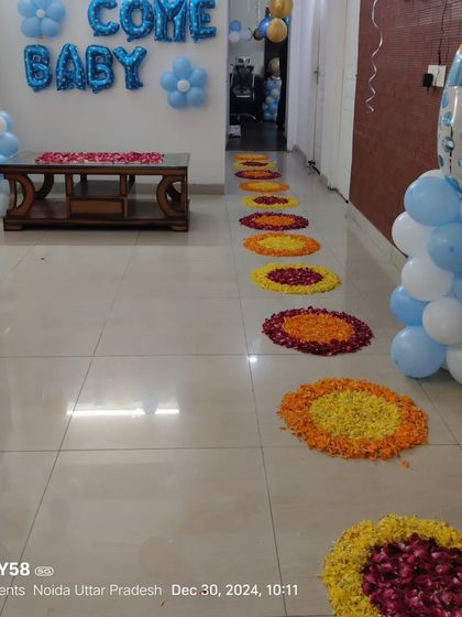 Another view of the 'Welcome Baby' home decoration, showing the balloon pillars and the flower petal pathway leading into the house.