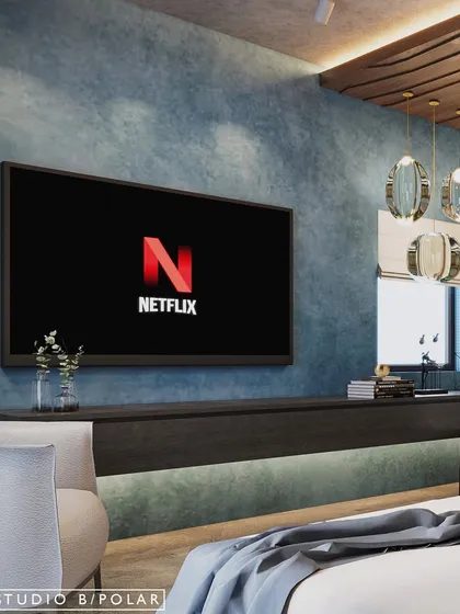 For a modern home in Gujarat, we used earthy materials like lime plaster and wood. The TV wall in this bedroom features a textured blue finish, with a floating console that extends into a study desk for a seamless look.