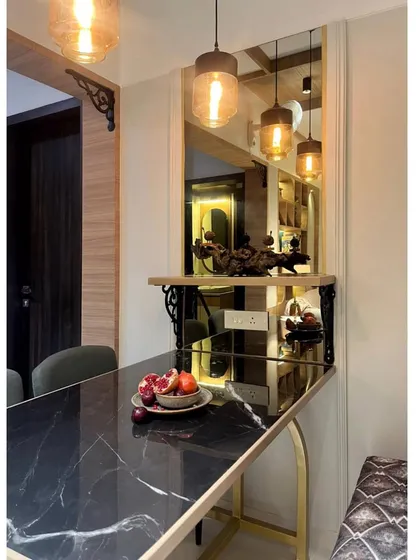 The black marble dining table reflects the warm light from the pendants, adding depth and a touch of luxury. The custom shelf with wrought iron brackets adds a rustic-industrial touch.