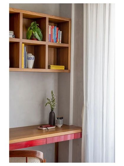 A custom-designed study desk with a lacquered red drawer, continuing the Channapatna-inspired theme. It is paired with a built-in teak bookshelf, creating a warm and inviting workspace.