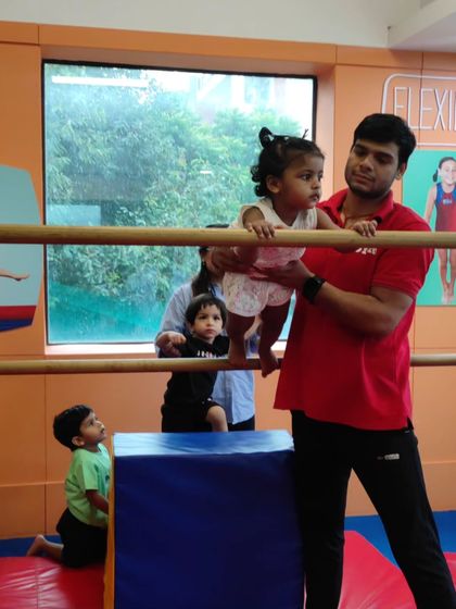 A toddler carefully watches her peers while waiting her turn, learning about patience and observation in a group setting.