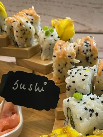 A close-up of our sushi display, showing the detail and care we put into each roll. The "Sushi" sign adds a charming touch to the live station or platter.
