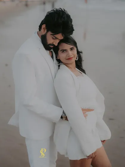 A stylish portrait of a couple on a Goa beach, dressed in all white. The soft evening light and the ocean backdrop create a serene and romantic atmosphere for this destination pre-wedding shoot.