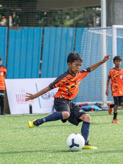 A player strikes the ball with perfect technique during a match in the Mini Dribblers League.