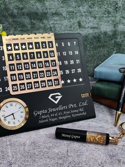 This professional mini combo set is perfect for corporate branding. It features a metal infinite calendar with a clock, a gold flake pen, and a matching keychain, all customized for "Gupta Jewellers Pvt. Ltd." with their logo and address.