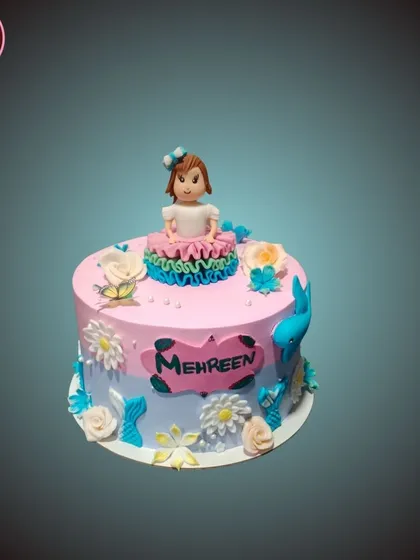 A sweet and simple cake with a pink and blue ombre effect, topped with a cute fondant girl figurine.