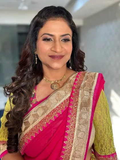 A beautiful mature client in a pink and yellow saree. The makeup is soft and enhances her natural beauty.