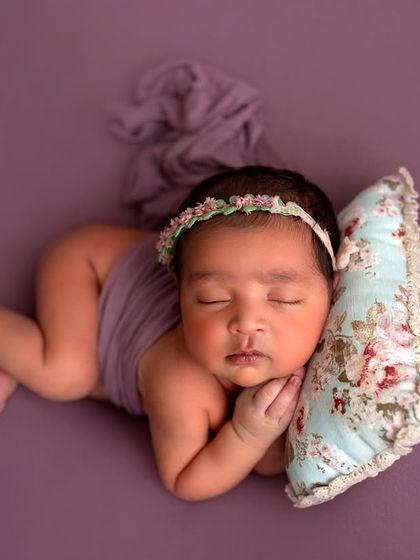 Another angle of this peaceful pose. The soft lighting and simple wrap highlight the baby's delicate features and tiny curled-up body.