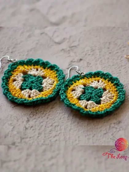 A pair of my mandala-style crochet earrings in green, yellow, and cream. These are lightweight and add a lovely bohemian touch to any outfit.