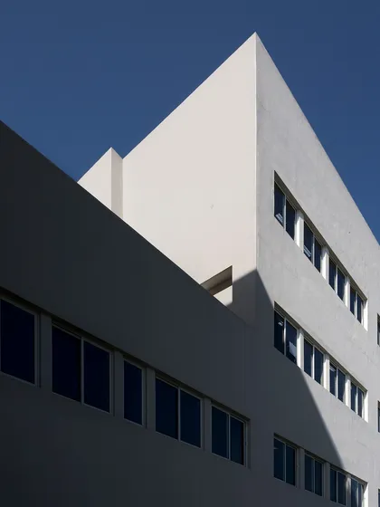 The geometric massing of the Sushant School of Design and Architecture creates a powerful play of light and shadow against a deep blue sky. The building's form is optimized along the North-South axis to facilitate natural ventilation.