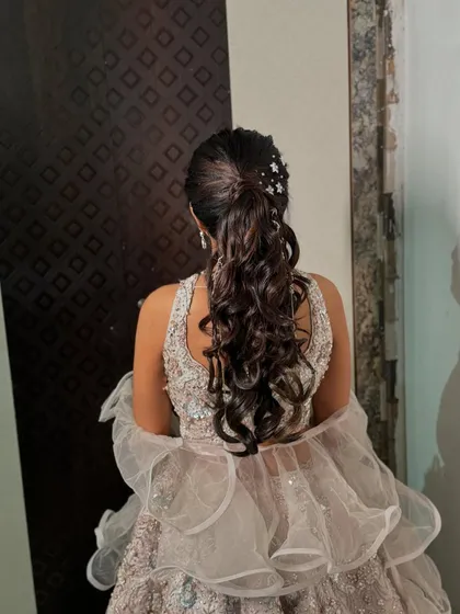 A starry night hairstyle for the sangeet. This curly ponytail is adorned with star-shaped clips for a fun and festive touch.