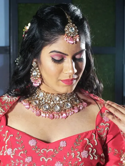 A close-up portrait from a studio garment shoot. This allows us to focus on the details of the blouse, the matching pink-accented jewelry, and the makeup, providing a complete look for a brand's catalog.