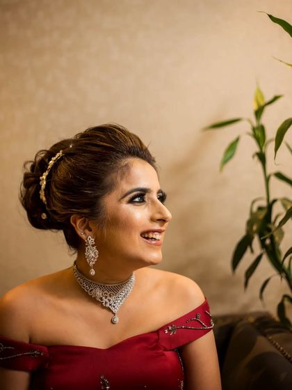 A happy, smiling portrait of a bride in a red off-shoulder gown.