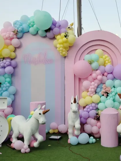 A magical unicorn-themed party in dreamy pastel colors. The setup includes unicorn props, a rainbow-arched backdrop, and a light-up number '5'.