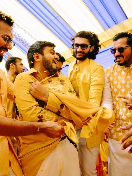 Friends and family joining in the 'phoolon ki holi', tearing the groom's kurta in jest. It's all about fun and making memories.