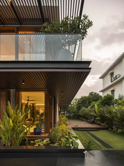 As evening falls, the warm interior lighting of Villa re:FORM highlights the clean lines of the architecture. The cantilevered balcony and lower-level glazing connect the home to its tropical landscape and bio-pond.