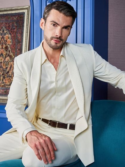 A closer look at the ivory tuxedo, showing the texture of the fabric and the subtle sheen of the hand-embroidered lapels. It's a testament to the master craftsmanship that goes into every piece.