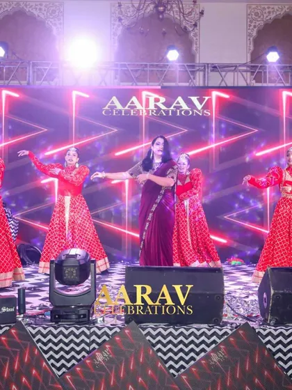 A graceful mother's performance, surrounded by dancers in red. The elegant choreography and dramatic lighting create a beautiful and emotional moment during the sangeet.
