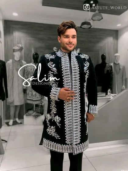 A client wearing a black open-front jacket with heavy silver embroidery over a black kurta. The layering adds depth and formality to the ensemble.