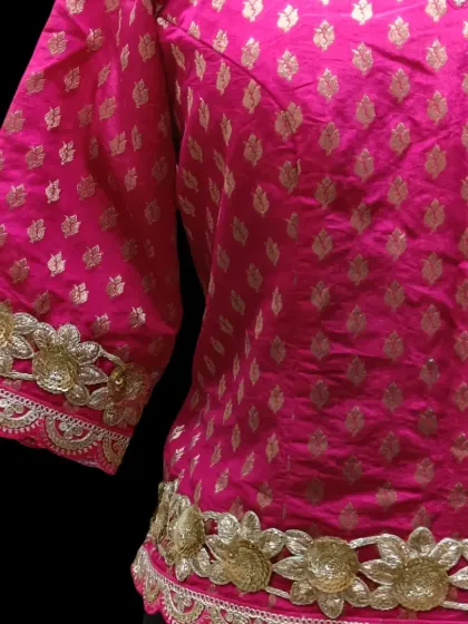 A detailed look at the craftsmanship on our pink long choli. The gold floral lace adds a luxurious finish to the rich brocade fabric.