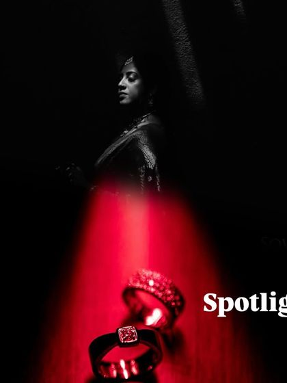 A creative and dramatic shot using a spotlight effect on wedding rings, with a silhouette of the bride in the background.