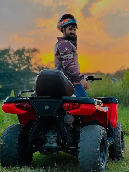 The right place can change the whole vibe. Here I am on my red Polaris Sportsman, taking a moment to enjoy the golden hour sunset over the lush green landscape.